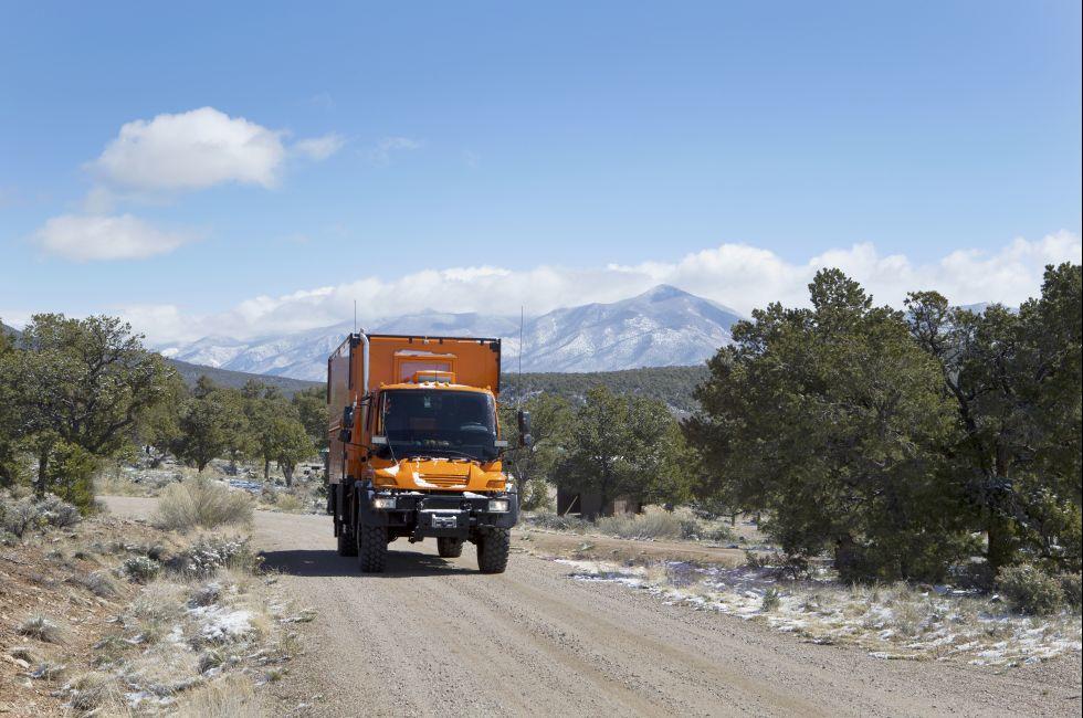WILD RIVERS RECREATIONAL AREA, NEW MEXICO, USA - April 15: Custom orange RV truck driving on snowy dirt road on April 15, 2014 at Wild Rivers Recreational Area, New Mexico, USA.  