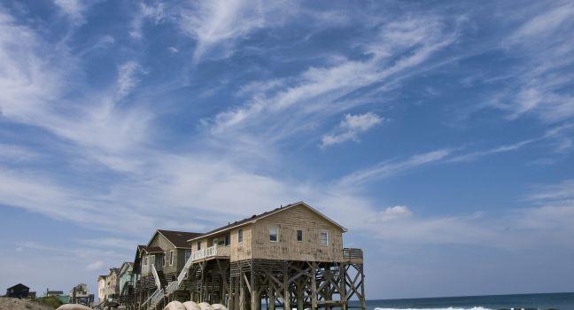 View from the beach showing a beautiful cloudscape and the sand bags around a row of condemned homes in Nags Head North Carolina in the Outer Banks.
