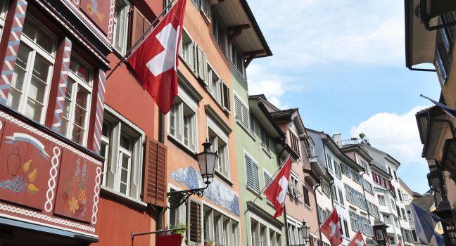 Old street in Zurich decorated with flags for the Swiss National Day, 1st of August; 