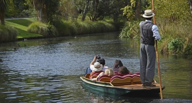 CHRISTCHURCH, NEW ZEALAND - MARCH 31, 2013: A boatman guides a group of tourists in their punt down the Avon River on Easter Sunday afternoon on March 31, 2013 in Christchurch.