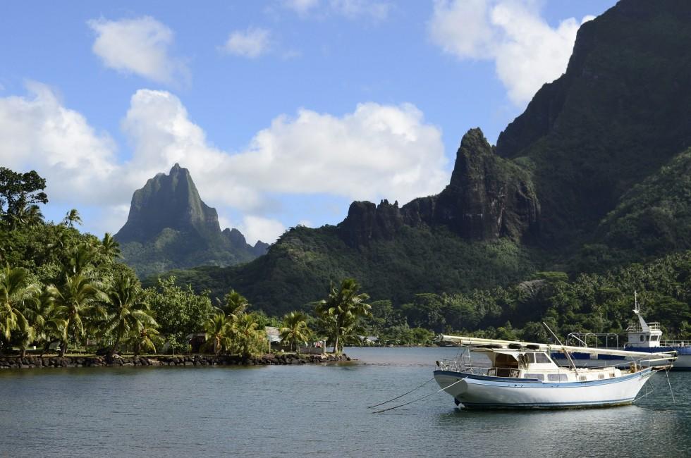 Boat in Cooks Bay with Moua Puta mountain in the background on the tropical pacific island of Moorea, near Tahiti in French Polynesia.; 
