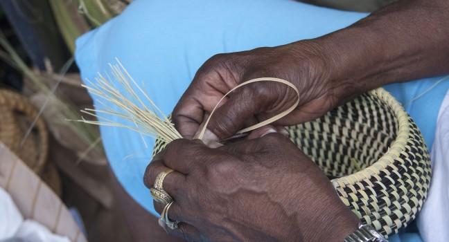 Hands weaving sweetgrass into beautiful baskets.