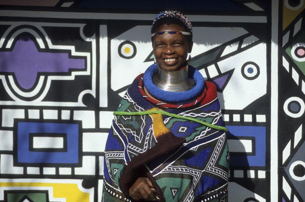Neck-stretching brass coils announce marrigage as do a beaded jocolo wedding apron that mirrors the primary colors of the decorations hand painted by the mguni-speaking Ndebele.  Bronkhorstspruit, South Africa