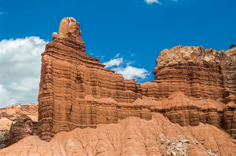 Chimney Rock, a red cliff of sandstone is backed by a deep blue sky in the Utah desert of Capitol Reef National Park.
