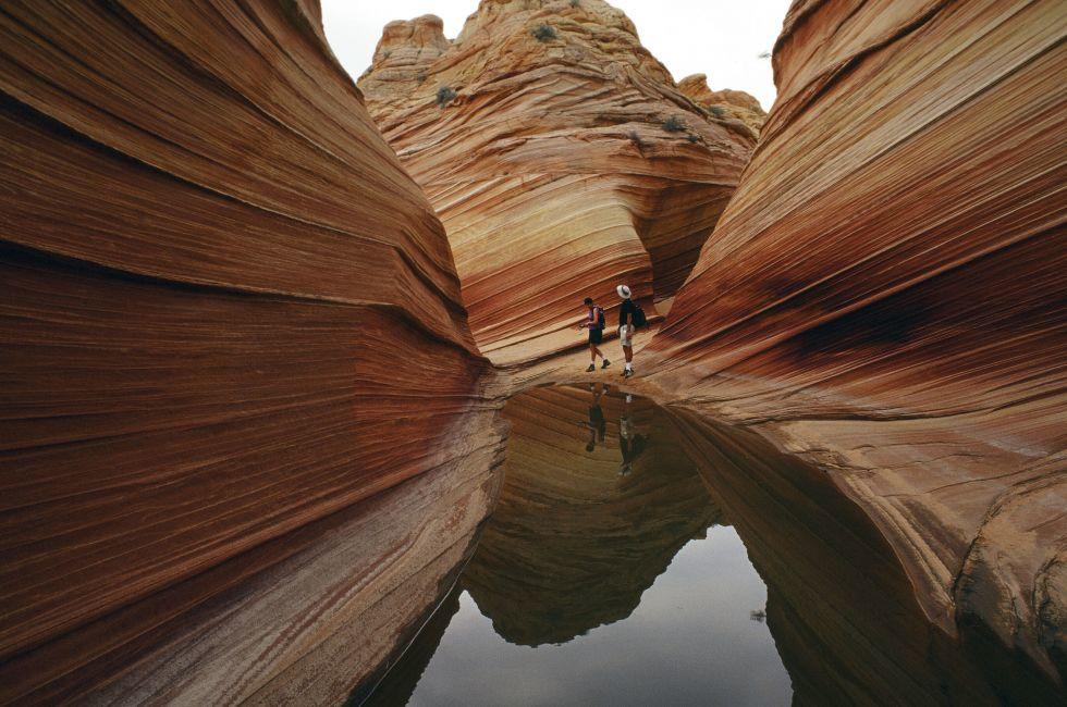 A lone hiker explores the astonishing candy stiped sandstone hidden amongst the geologic folds of the Colorado Plateau.
