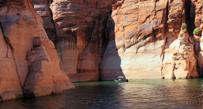 Lake Powell, in Glen Canyon spans 186 miles  in Utah and Arizona.  its coastline is populated with colorful sandstone cliffs,  pristine blue green water, islands, rock formations, resorts and marinas