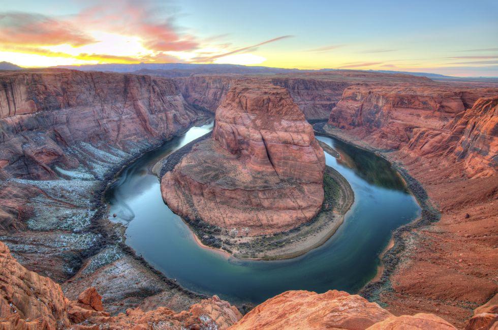 Winter sunset at Horseshoe Bend, Page, Arizona, United States. snow on the ground eroded red rock sandstone colorado river 180 degree turn headland.