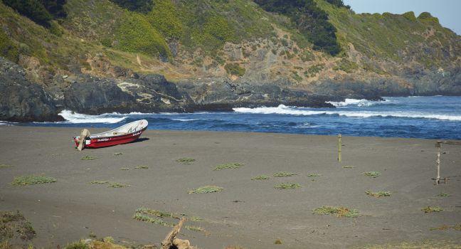 Colourful wooden fishing boat on the beach in the small coastal village of Cobquecura in Maule, Chile.