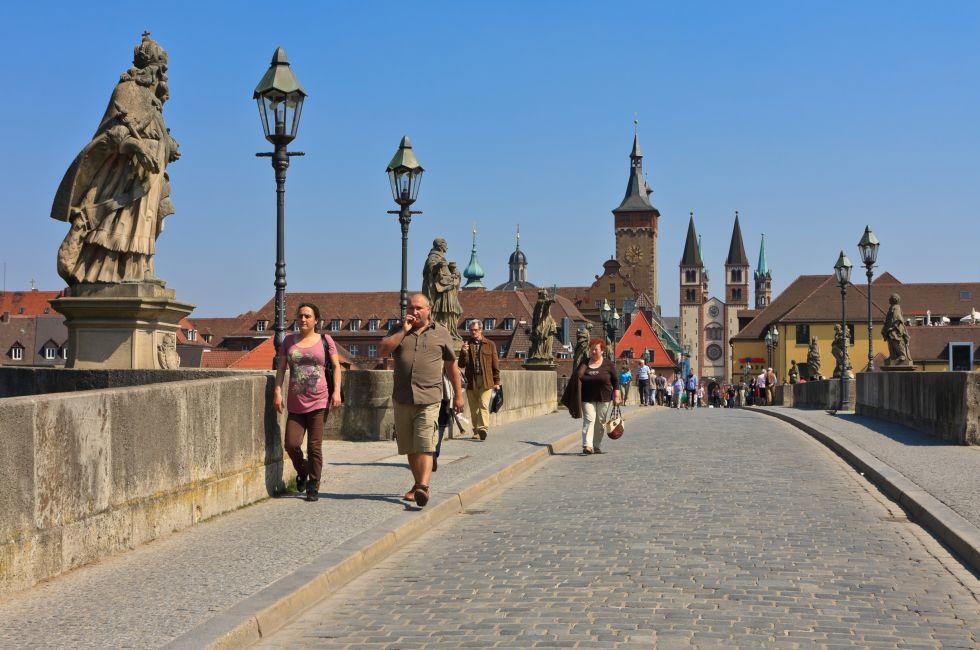 WURZBURG, GERMANY - APRIL 20th 2011: People walking over the Alte Mainbrucke in Wurzburg with many nice statues of saints is known as the oldest bridge (built 1473-1543) on a sunny spring day