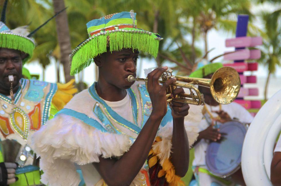 Male dancers dressed in traditional costumes performing at a Junkanoo festival playing a trumpet in Freeport, Bahamas