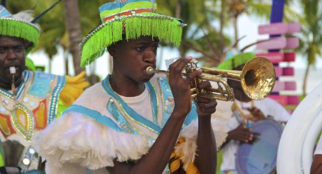 Male dancers dressed in traditional costumes performing at a Junkanoo festival playing a trumpet in Freeport, Bahamas