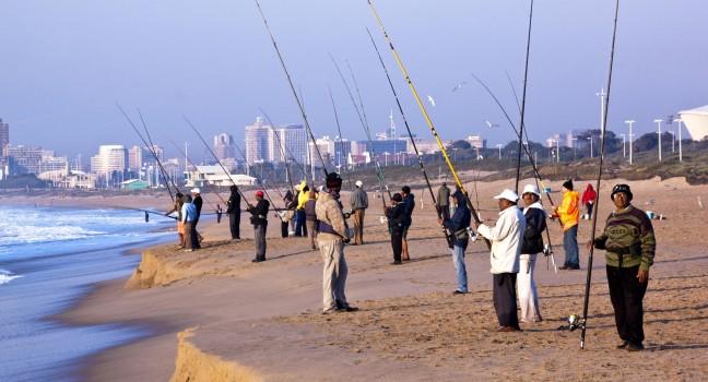 DURBAN, SOUTH AFRICA - JULY 2, 2014: Many unknown early morning fishermen fish on Blue Lagoon beach in Durban South Africa; 