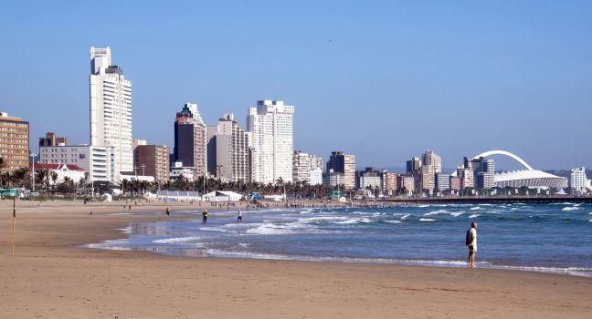 DURBAN, SOUTH AFRICA - DECEMBER 18, 2014: Many unknown people on South Beach against &quot;Golden Mile&quot; city skyline in Durban, South Africa