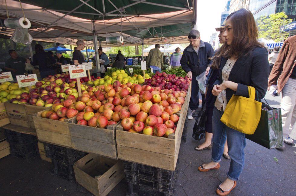 NEW YORK CITY - APR. 20: Woman selects produce at Union Square Greenmarket in NYC on Apr 20, 2012. This world famous farmers' market began in 1976 and has grown to 140 farmers during peak season.; Shutterstock ID 100566316; Project/Title: Weekend Getaways;