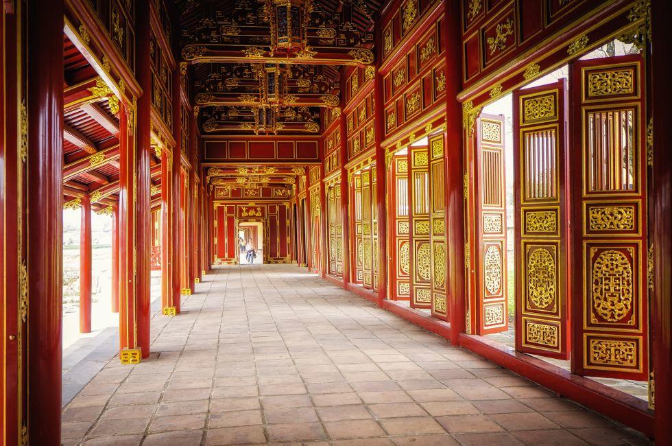 Red doors, wall panels, and ceiling, painted with gold, provide a dramatic hallway in a building of the Imperial Citadel in the city of Hue, central Vietnam.